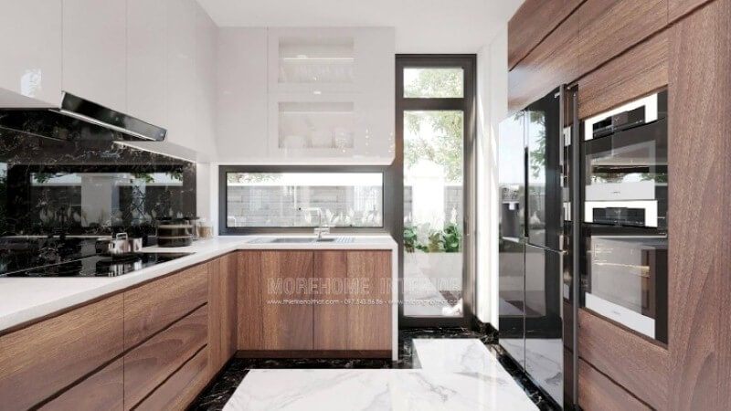 Là một trong những xu hướng trang trí nội thất nổi bật trong những năm tới, trang trí phòng bếp hiện đại tôn lên vẻ đẹp mộc mạc nhưng không kém phần sang trọng của gỗ điển hình là gỗ óc chó tự nhiên. Loại gỗ rất được ưa chuộng trong các siêu xe bởi vẻ đẹp ấn tượng từ vân, màu gỗ. Như trong ý tưởng bố trí phòng bếp tại biệt thự Vinhomes Imperia Hải Phòng, sự hài hòa tôn lên nét đẹp giữa truyền thống và hiện đại, tủ bếp dưới gỗ óc chó và tủ bếp trên gỗ công nghiệp trắng bóng.